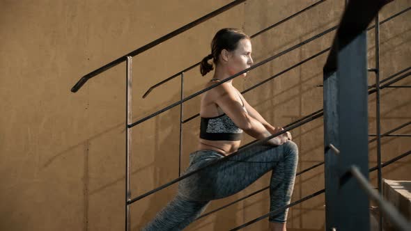 Fitness woman stretching legs on stairs before workout alt