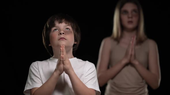 Portrait of Beaten Boy and Girl Praying Holding Hands Together Looking Up alt