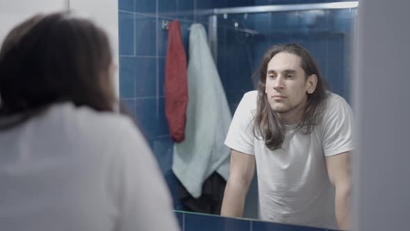 Young Man Looking Himself in a Mirror and Thinking About His Day  Middle Shot alt