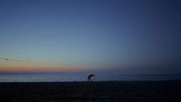 Silhouette Athlete Girl Exercising on Seacoast at Dusk alt