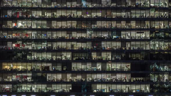 Panning up view of office windows with working people alt