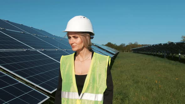 Industrial Woman Engineer in Uniform Walking Through Solar Panel Field for Examination alt