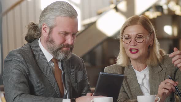 Senior Business Partners Using Tablet and Talking in Restaurant alt