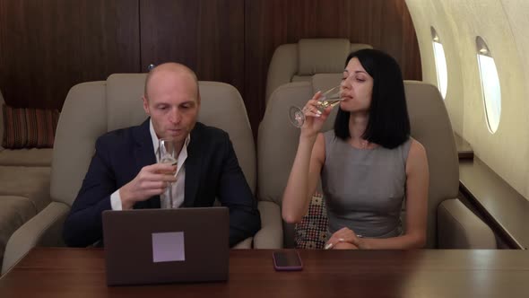 Young Couple Man Woman clink Glasses and Drink Champagne, Fly Business jet Private Jet alt