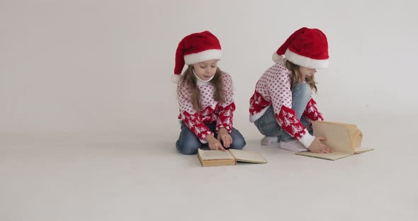 Little Girls in Santa Hats Reading Books.