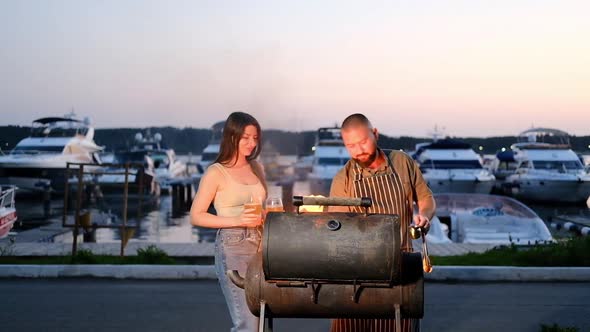 Outdoor barbecue in evening at sunset against background of yachts and ships alt