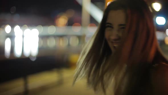 Teenage girl laughing at making funny faces outdoors at night