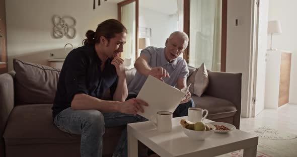 Father and Son Examining Photos Together alt