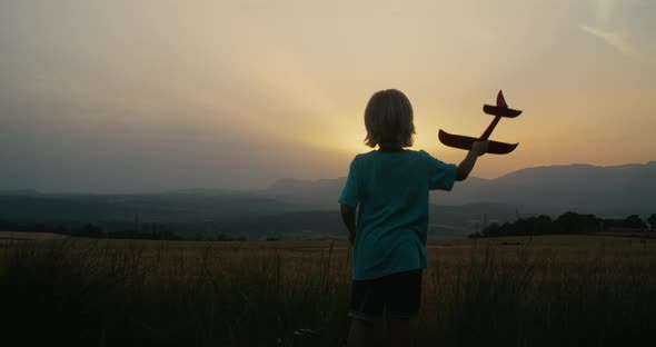 Dreaming Child Boy Play with Toy Airplane on Epic Landscape on Sunset alt