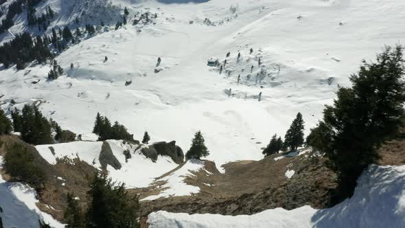 Drone flying over mountain ridge, revealing beautiful valley covered in snow alt