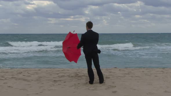 Male opening an umbrella on a beach alt