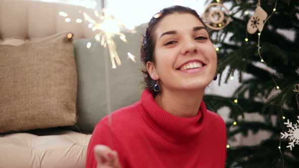 Happy Attractive Young Woman Sitting on the Floor By the Christmas Tree Celebrating Xmas with alt