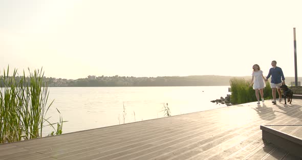 Young European Couple Going Near Lake with Dog alt