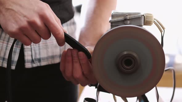 The Craftsman Is Sharpening the Edges of a Belt on a Special Machine alt