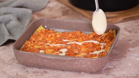 Tasty meat lasagne is poured with white creamy bechamel sauce. The process of making lasagna.