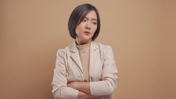 Asian business woman feel confused standing and looking at camera isolated over beige background.