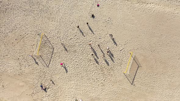 AERIAL: Rotating Shot of People Standing in Football Court with Long Shadows on Sand