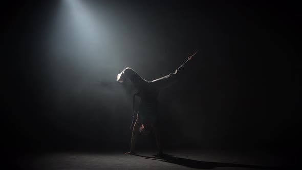 Curly Maiden Practicing Capoeira in Darkness Against Spotlight in Studio. alt