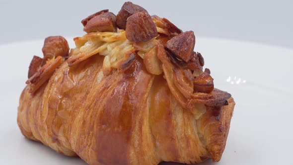 Almonds croissant on white plate rotating in front of camera
