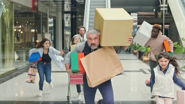 Group of Shopaholics With Bags Running Along Mall Hurrying To Make Purchases on Black Friday alt