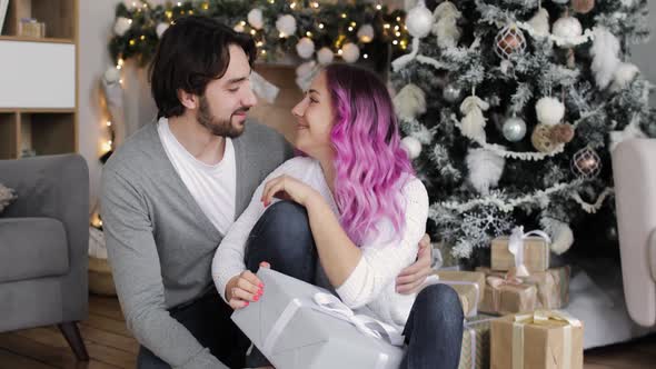Portrait of Young Couple Man and Woman Are Sitting Together Near Christmas Tree alt
