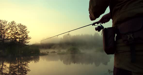 Unrecognizable Man Fishing in Lake at Dawn