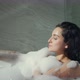 Cute Woman Playing with Bath Foam in Hotel Bathroom. Sexy Girl Lying in Bath.