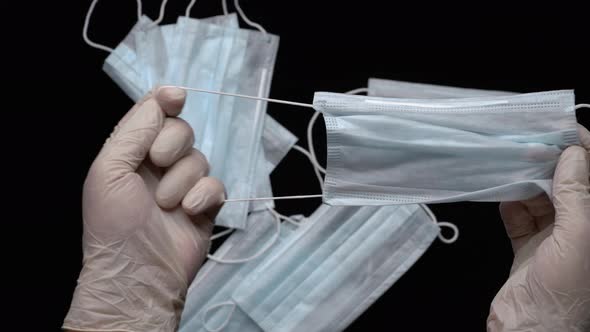 Doctor Showing Medical Face Mask Holds Equipment in Hands Protected by White Medical Gloves