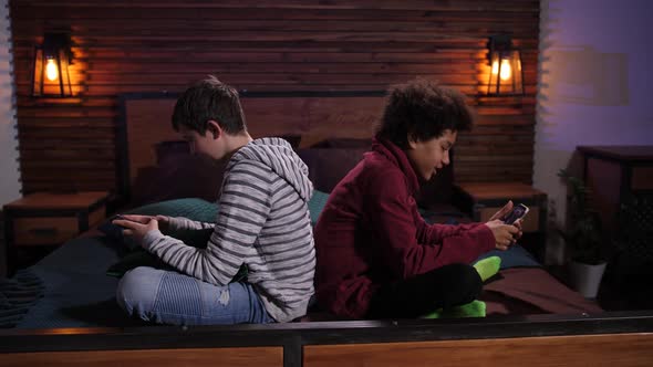 Mixed Race Teens Playing Video Games on Phones alt