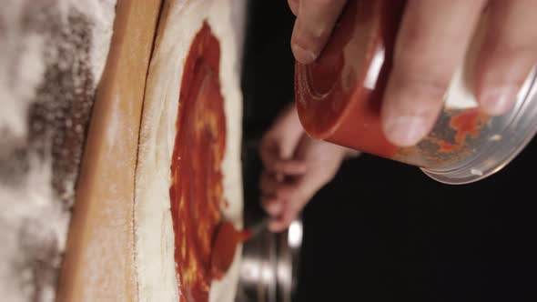 Slow Motion Of Ready-made Pizza Sauce Being Spread On Pizza Dough Before Baking. close up, vertical alt