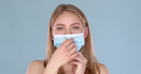 Adorable Smiling Young Girl Taking on Her Face Mask Against Viruses