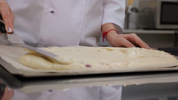 Closeup of the Pastry Chef Spreading the Dough in Baking Dish with a Spatula alt