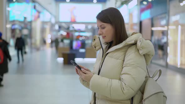 Young Woman in Shopping Mall or Trade Center Using Smartphone Mobile Phone