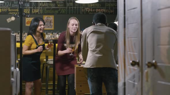 Diverse girls cheering for men playing table game inside the bar