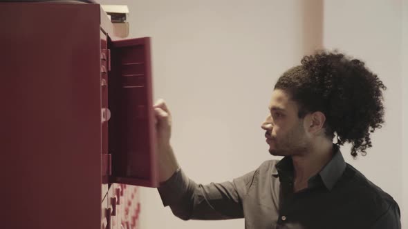 Young man putting book in locker