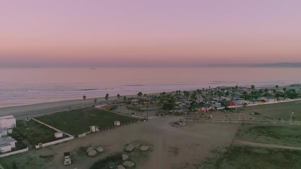 Aerial Drone shot flying over a small city in mexico to the ocean just after the sun has set. alt