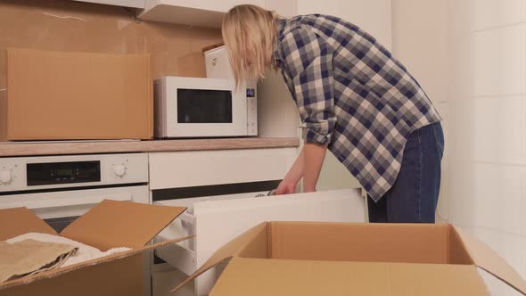 A Woman Takes Dishes Out of a Cardboard Box