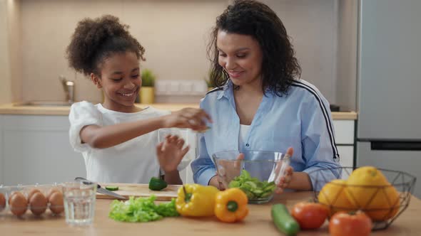 Cheerful Mother and Daughter Prepare Salad in the Kitchen Family Day African Girl Helps Her Mother alt