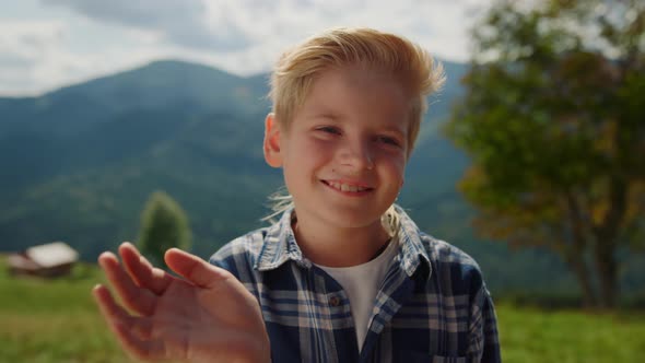 Smiling Boy Waving Hand on Green Meadow Close Up alt