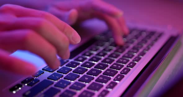 Typing on notebook computer with red and blue light alt