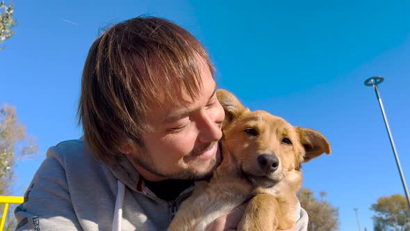 Close Up Shot of Young Bearded Man Hugging and Kissing His Cute Friend Brown Dog alt