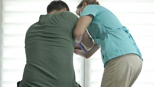 Doctor or Nurse is Helping an Patient to Get to Her Feet alt