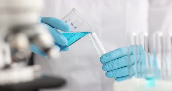 Gloved Chemist Pouring Blue Liquid From Flask Into Test Tube in Laboratory  Movie alt