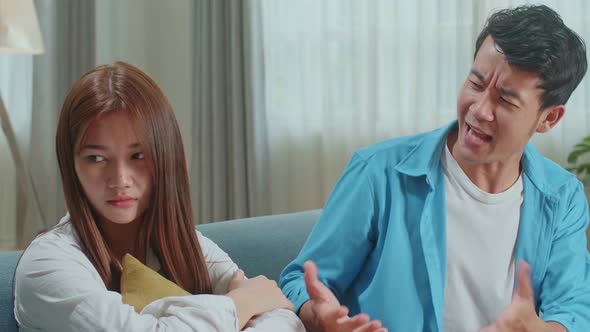 Couple Arguing. Angry Young Asian Man Blaming Woman In The Living Room At Home alt