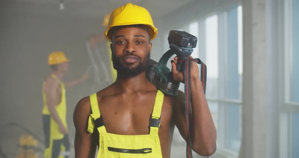 African Sexy Muscular Builder Posing Shirtless with Drill Slung Over His Shoulder alt