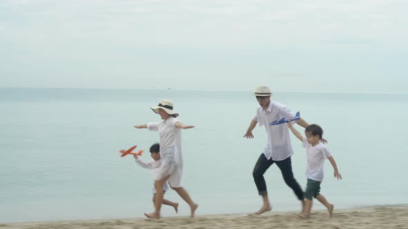 Happy asian family having fun and cheerful with straightened arm same a plane on the beach. alt