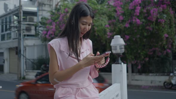 Being Amazed a Lady Surfing Her Smart Phone Sitting on the Border Wall alt