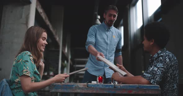 Young couple sitting at a restaurant table waiter brings menucarts for them alt