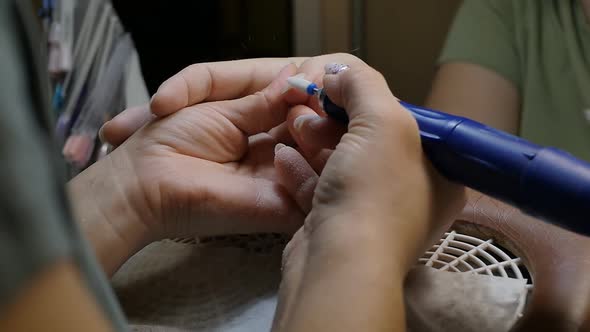 Manicurist Removes the Old Layer of Varnish From the Nail with a Special Device alt