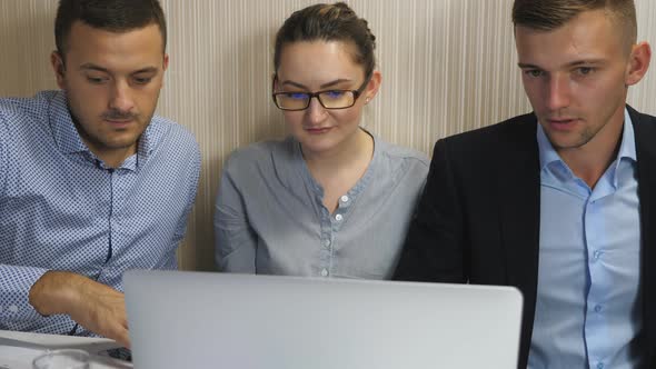 Young Coworkers Examining Financial Reports on Computer at Office alt